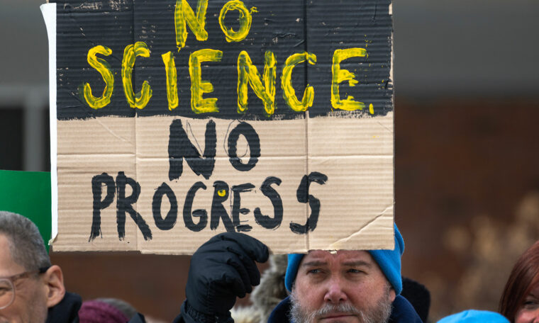 Man håller upp skylt med texten ”No science no progress”
