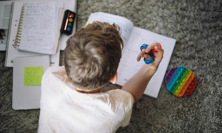 pojke gör läxor på golvet med fidget spinner i handen