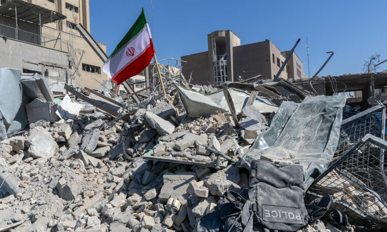 En iransk flagga i rasmassorna vid en bombskadad polisstation i Teheran, Iran.