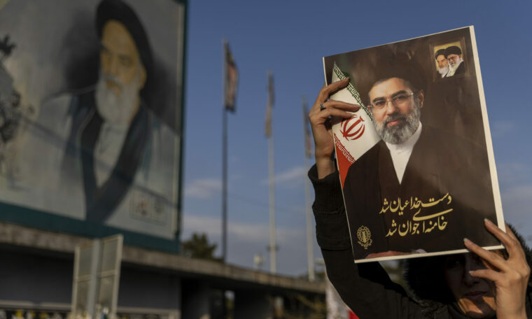 Kvinna håller upp en bild på Mojtaba Khamenei.