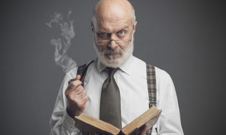 Gammaldags manlig professor röker pipa och läser en gammal bok.